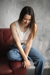 Portrait of a young attractive girl in a white T-shirt and jeans. A girl of oriental appearance in the interior of a stylish apartment. Lifestyle