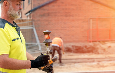 Site engineer surveyor using rugged tablet controller computer to operate EDM total station for setting out and surveying close-up