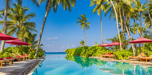 Panoramic holiday landscape. Luxury beach poolside resort hotel swimming pool, beach chairs beds umbrellas palm trees, relax lifestyle, blue sunny sky. Summer island seaside, leisure travel vacation