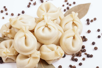 Uncooked dumplings with peppercorns and bay leaves on white background. Dumplings closeup.