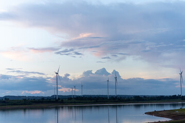 Evening view of windmill fields on water surface and beautiful sky in Chaiyaphum, Thailand.