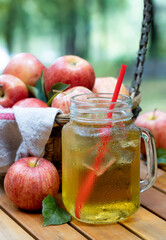 Cold apple juice with fresh apples outdoors on table