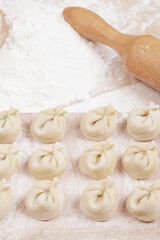 Dumplings on a wooden board, flour and rolling pin on the table. Homemade dumplings closeup.