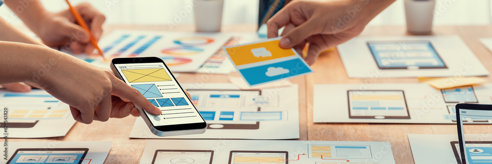 Poster Panorama shot of front-end developer team brainstorming UI and UX designs for mobile app on paper wireframe interface. User interface development team planning for user-friendly UI design. Scrutinize