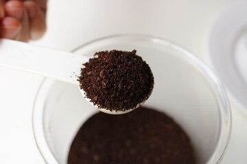 Close up gound coffee on white plastic spoon.