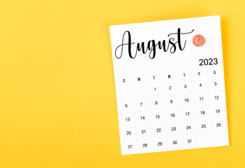 The August 2023 and wooden push pin on yellow background.