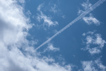 Kondensstreifen eines Flugzeugs am Wolkenhimmel
