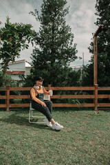 Portrait of happy Asian Woman in the park ,wearing a wireless headphone , holding a cup of coffee