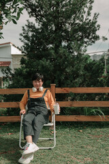 Portrait of happy Asian Woman in the park ,wearing a wireless headphone , holding a cup of coffee