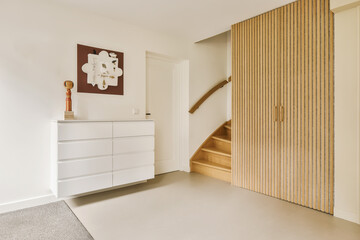 a room with white walls and wood paneling on the wall, there is a staircase leading up to the second floor