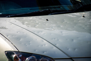 Car hood damaged by major hailstorm hailstones. Car insurance repair dents. Dented car bonnet - obrazy, fototapety, plakaty
