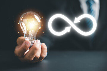 Man reveals light bulb with infinite symbol icon, illustrating creative new idea. Innovation, unlimited brainstorming, inspiration, and solution. Development and data exchange for business growth.