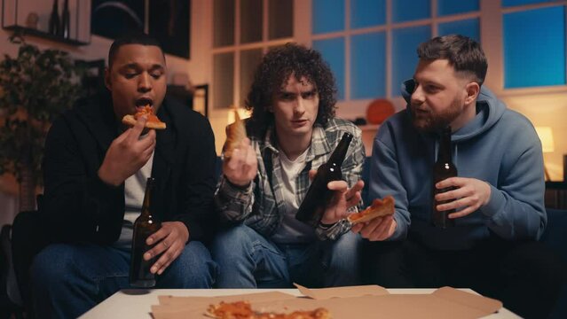 Three guys friends eating pizza and drinking beer, bachelor's party, home party