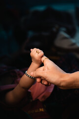 baby holding finger of her mother 