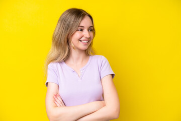 Fototapeta premium Blonde English young girl isolated on yellow background with arms crossed and happy
