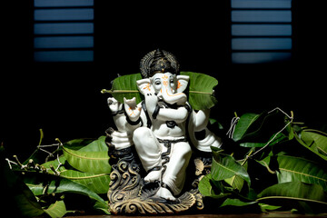 Ganesh statue in front of mango leaves