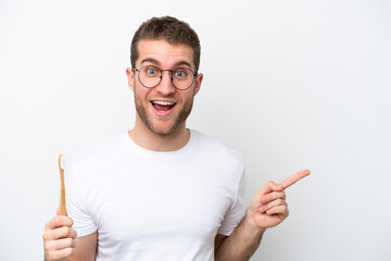 Young caucasian woman brushing teeth isolated on white background surprised and pointing finger to...