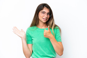 Fototapeta premium Young caucasian woman isolated on white background holding copyspace imaginary on the palm to insert an ad and with thumbs up