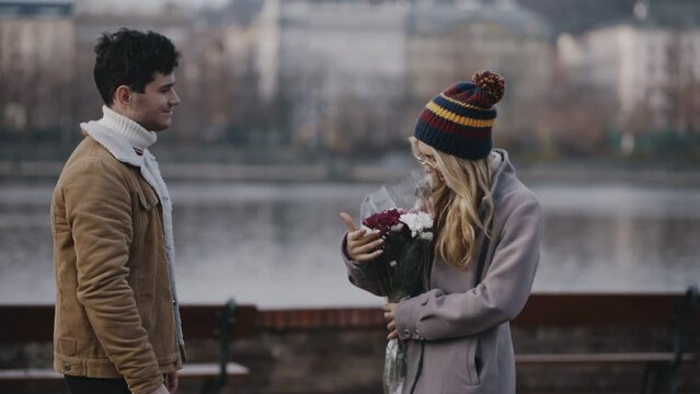 Young married couple mading romantic date for holiday on embankment of river. First meeting after chatting on meeting website. Man and woman walking around city on weekend or vacation together.