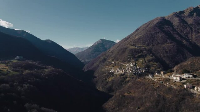 Aerial view of the small village of Pagnona in Valsassina, surrounded by the mountains of the Lombardy Alps. Blue sky