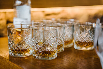 Serves glasses of whiskey, scotch, whisky, brandy on bar. Catering service concept. Closeup. Reception guests at party in restaurant. Hard strong alcoholic drinks in assortment: cognac, vermouth, rum.