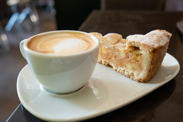 Piece of an apple pie and cup of coffee espresso on wooden table. Shallow focus