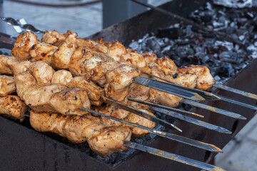 Tender and juicy chicken skewers are cooked on the coals in an open grill. Delicious kebab or barbecue