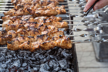 Cook cuts a piece of chicken meat cooked over an open fire to determine the degree of readiness. Grill, barbecue, picnic
