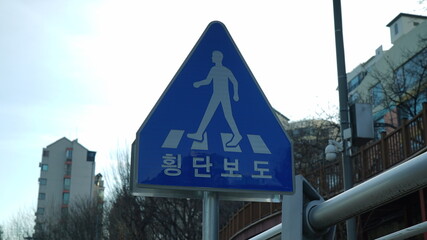 A blue traffic sign on a street in South Korea, text means Crosswalk