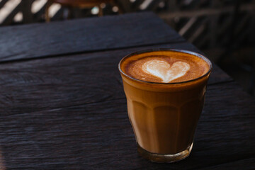 Fragrant cappuccino with a heart in a glass mug on the table