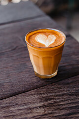 Delicious cappuccino in a glass mug on a wooden table