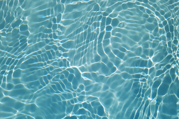 Blue water with ripples on the surface. Defocus blurred transparent blue colored clear calm water surface texture with splashes and bubbles. Water waves with shining pattern texture background.