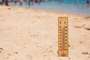 Thermometer on sand showing high temperature. Hot weather and climate concept
