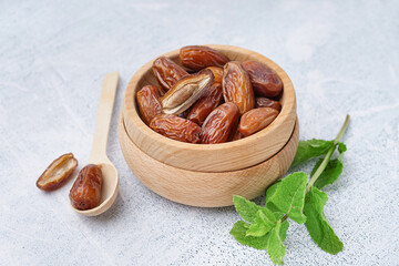 Bowls with dried dates on light background