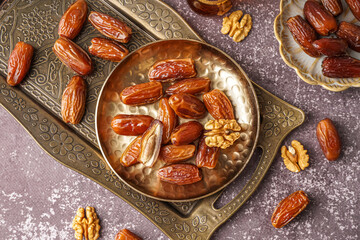 Plate with dried dates and nuts on grey background