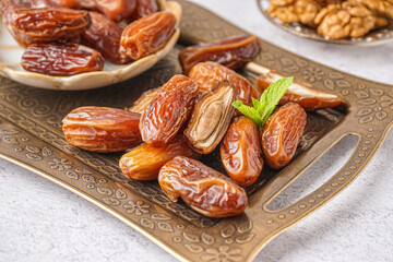 Tray with dried dates on light background