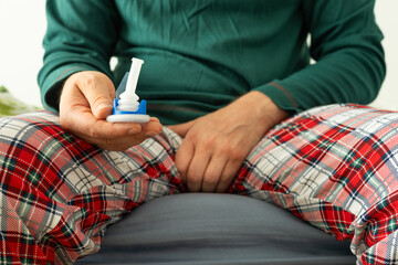Urology, problems with urination in men. Health concept, A man in pajamas holds a catheter in his...