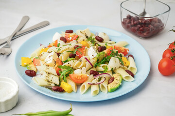 Plate of tasty pasta salad with tomatoes and beans on white background