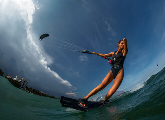 Female Kite surfer riding a kiteboard on the sea with splash.