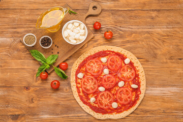 Tasty pizza and ingredients on wooden background