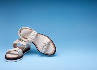 Comfortable summer women's sandals on a gradient blue background with copy space on the top and on...