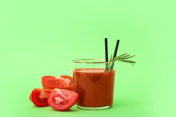Glass of tasty tomato juice on green background