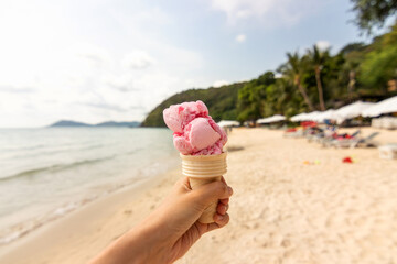 Fototapeta na wymiar Hand holding ice cream cone on the beach in summer day.