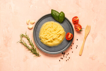 Plate of tasty mashed potatoes with tomatoes and basil on pink background