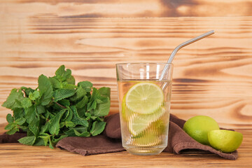 Glass of infused water with lime and mint on wooden background