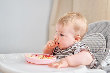 Cute child eats healthy food vegetables and meatballs from dietary meat steamed,. Portraits of a cute 10 months old baby girl. The baby sitting in a special high chair for babies.