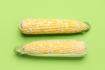 Fresh corn cobs on green background