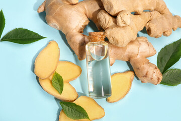 Bottle of ginger cosmetic oil and leaves on blue background