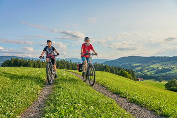two senior girlfriends having fun during a cycling tour in the Allgau Alps near Oberstaufen,...