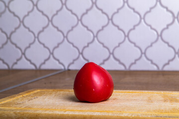 tomato lies on a wooden plank in the interior of the kitchen